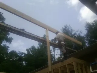 Carpenter setting a ridge beam over a new addition frame — Ice Dam Removal by Roofing Brothers in Garland